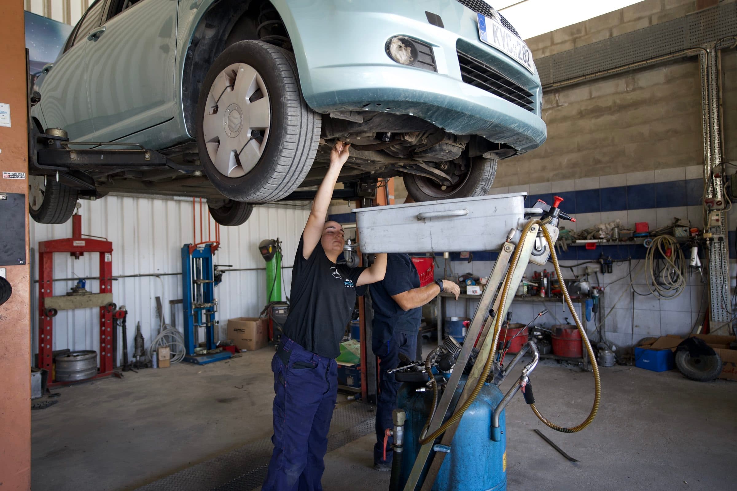 Two mechanics working under a car on the lift