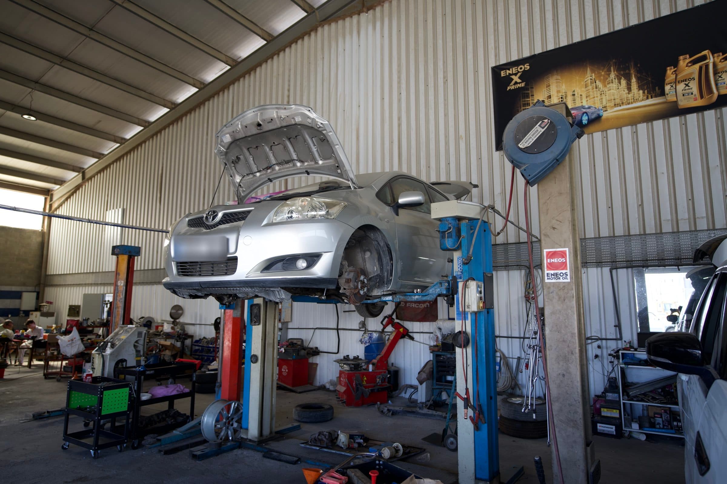 A car on the lift with the bonnet up and a front wheel off